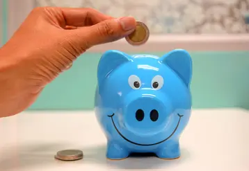 Tirelire bleue dans laquelle une main dépose une pièce de monnaie..