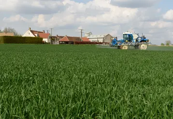  Pulvérisateur dans un champ près d’habitations