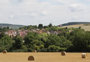 paysage rural avec champ et bottes de paille au premier plan et village en arrière plan