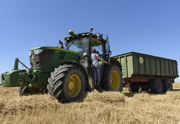 Jeune femme de dos en train de monter sur un tracteur dans un champ