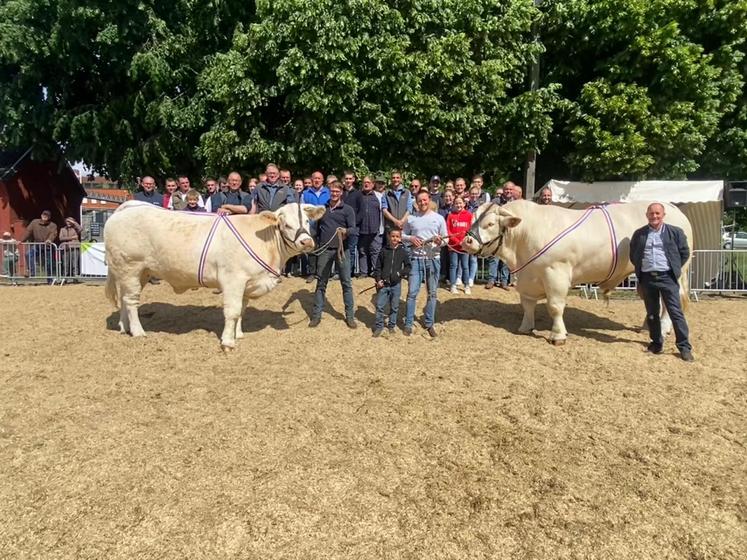À gauche, Paul Blondel avec sa vache ; à droite, la famille Gomel accompagnée de leur taureau. En arrière-plan, l'ensemble des éleveurs participants.
