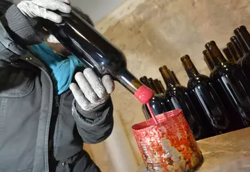 Cachetage des bouteilles à la cire au château Le Puy (Famille Amoreau). Production de vins naturels dans le Bordelais. Méthode ancienne traditionnelle. Tradition ...